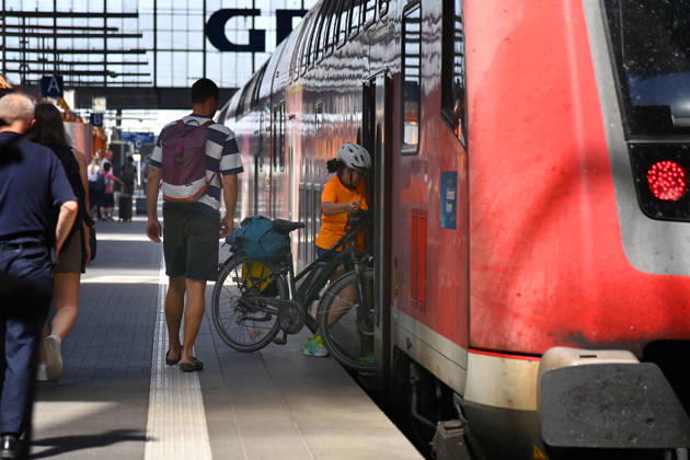 Themenfoto DB, Deutsche Bahn. Frau steigt mit Fahhrad in einen Regio Zug. Bahnreisende im Hauptbahnhof Muenchen,DB,Die Bahn, Fernverkehr,Hauptbahnhof Muenchen, Regiozug,Regionalverkehr,Lokomotive.