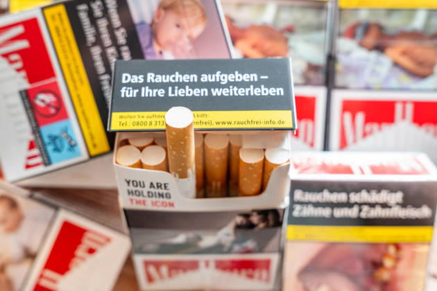 Mehrere Schachteln Zigaretten und eine geöffnete Zigarettenschachtel mit Warnhinweisen (wie: das Rauchen aufgeben - für Ihre Lieben weiterleben) zum Rauchstopp. Das Bild steht für die Gesundheitsrisiken des Rauchens, Nikotinabhängigkeit sowie Prävention und die Motivation, mit dem Rauchen aufzuhören und die Belastung durch Erkrankungen