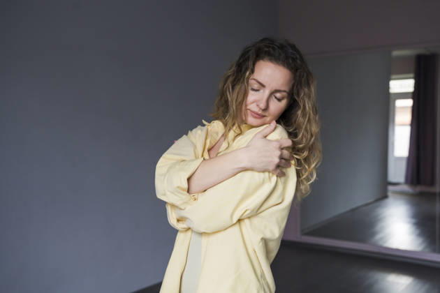 Yogini in yellow shirt hugging body indoors for self care model released, Symbolfoto, OSF02770