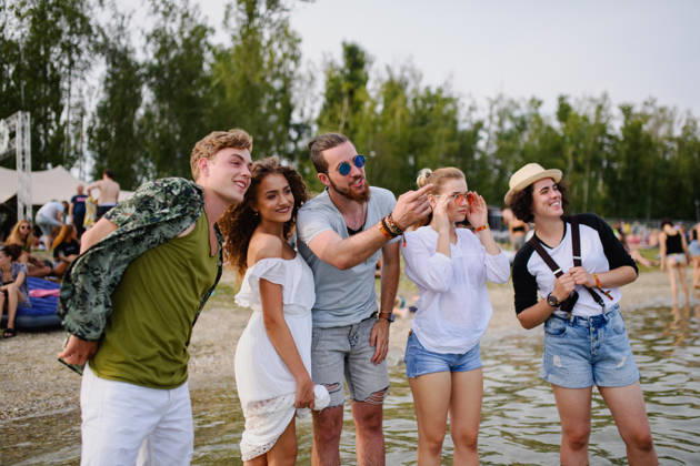 Group of young friends at summer festival. Group of cheerful young friends at summer festival, standing in lake water. model released