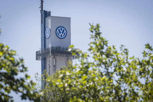 Turm vom VW-Werk in Osnabrück mit VW Logo bei blauem Himmel, vom Laub grüner Bäume umrahmt. Symbolbild Volkswagen Osnabrück. 11.07.2026 Symbolbild VW Osnabrück