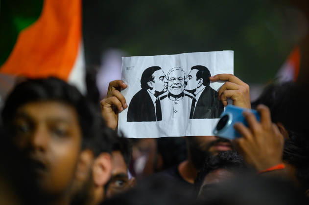 July 20, 2026, New Delhi, New Delhi, India: A protester holds up a placard depicting billionaires Mukesh Ambani and Gautam Adani kissing the cheeks of Prime Minister Narendra Modi, symbolizing protesters allegations of a corruption nexus between the two industrialists and the Modi government, at Jantar Mantar during demonstrations by the Cockroach Janata Party (CJP) demanding the resignation of Education Minister Dharmendra Pradhan over alleged irregularities in the NEET-UG exam, July 20, 2026. New Delhi India - ZUMAm184 20260720_zip_m184_010 Copyright: xAnkitxRoyxMajumderx