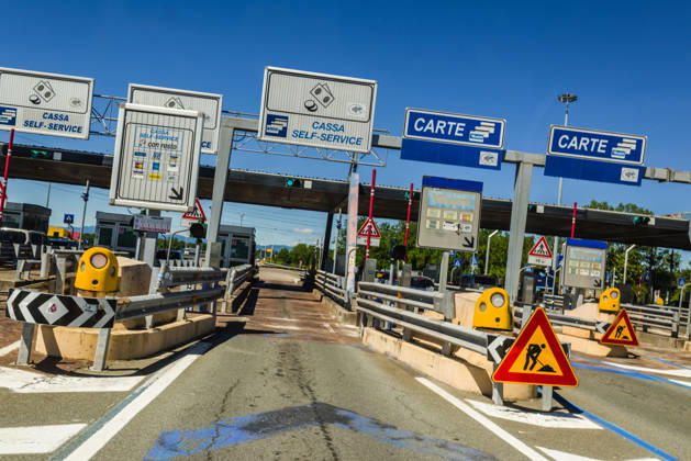 Blick aus einem Fahrzeug auf die Einfahrt einer Autobahnmautstelle. Italien. An einer Mautstelle in Italien