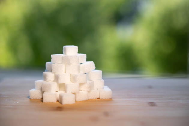 Stack of sugar cubes on a kitchen board. Stack of sugar cubes on a kitchen board. Blurred trees in the background. Swet food, white or industrial sugar. food_sugar_B97A0064
