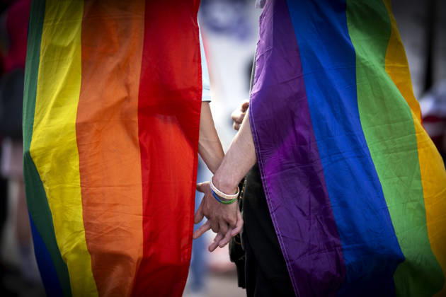 CSD-Anschlag Solidaritaets-Demo DEU, Deutschland, Germany, Berlin, 02.08.2026 Zwei schwule Maenner halten Haende mit Symbol Fahne in Regenbogenfarben auf der Trauerveranstaltung und Gedenkveranstaltung im Rahmen einer Demonstration und Kundgebung in Solidaritaet fuer die Opfer des islamistischen CSD-Anschlags und dessen Abbruch unter dem Motto Angriff auf den CSD Berlin Von Trauer zu Wut Zu Widerstand und Liebe ist staerker als Hass am Alexanderplatz in Berlin Deutschland . Bei dem Terroranschlag im Park Tiergarten starb ein Mensch und weitere wurden teils schwer verletzt. Der Anschlag erfolgte auf der Demonstration der schwul-lesbischen Gedenkparade Christopher Street Day CSD Parade Berlin Pride 2026 fuer die Rechte der LGBTQ+ Community in