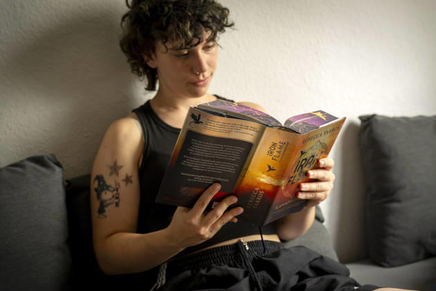 07.08.2026, Buchreihe von Rebecca Yarros, IRON FLAME, ein Teenager in Bad Wörishofen in Bayern sitzt auf ihrem Sofa und liest ihr Spannendes Buch. (Modelreleased) 07.08.2026, Jugendbücher 07.08.2026, Jugendbücher