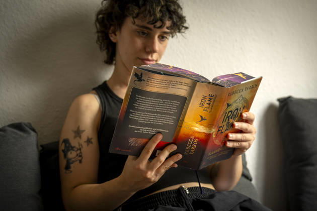 07.08.2026, Buchreihe von Rebecca Yarros, IRON FLAME, ein Teenager in Bad Wörishofen in Bayern sitzt auf ihrem Sofa und liest ihr Spannendes Buch. (Modelreleased) 07.08.2026, Jugendbücher 07.08.2026, Jugendbücher