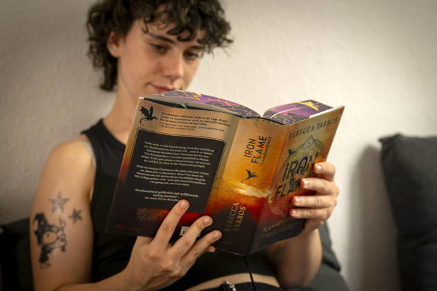 07.08.2026, Buchreihe von Rebecca Yarros, IRON FLAME, ein Teenager in Bad Wörishofen in Bayern sitzt auf ihrem Sofa und liest ihr Spannendes Buch. (Modelreleased) 07.08.2026, Jugendbücher 07.08.2026, Jugendbücher