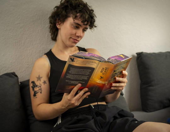 07.08.2026, Buchreihe von Rebecca Yarros, IRON FLAME, ein Teenager in Bad Wörishofen in Bayern sitzt auf ihrem Sofa und liest ihr Spannendes Buch. (Modelreleased) 07.08.2026, Jugendbücher 07.08.2026, Jugendbücher