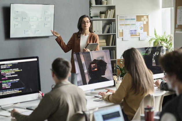 Female teacher explains programming to student group in classroom model released, Symbolfoto property released, DSHF02882