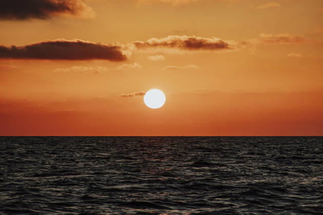 The bright sun sets over the calm ocean water, GMLF02273