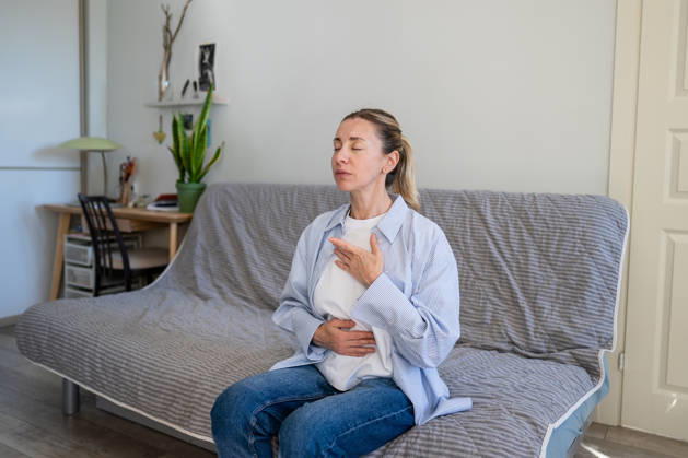 Eine positive, reife Frau, die zu Hause Selbsthilfetechniken zum Stressabbau und zur Tiefenatmung praktiziert. Calm mature woman do stress relief deep breathing self helping therapy, female sitting on sofa holding hands on chest inhaling air, focusing on physical and mental relaxation, healing zen practice (License=RF) ,model released, Symbolfoto Copyright: xZoonar.com DmitriixMarchenkox 25424105 ,model released, Symbolfoto ,property released