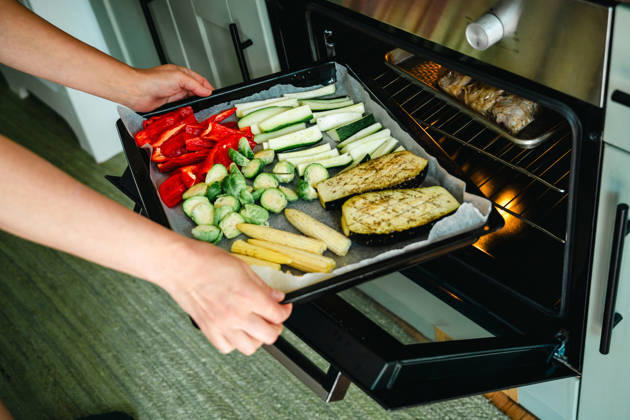Placing a colorful tray of vegetables into the oven Corby, England, United Kingdom R_ATMT260818-2108729-01 ,model released, Symbolfoto ,property released