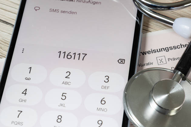 Symbolbild: Nahaufnahme von einem Überweisungsschein für einen Facharzt und ein Smartphone mit der angezeigten Nummer 116117 (Patientenservice) Copyright: xUdoxHerrmannx