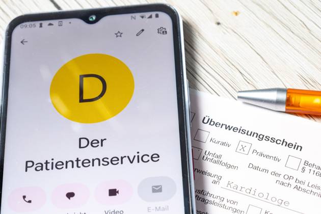Symbolbild: Nahaufnahme von einem Überweisungsschein für einen Facharzt und ein Smartphone mit der angezeigten Nummer 116117 (Patientenservice) Copyright: xUdoxHerrmannx