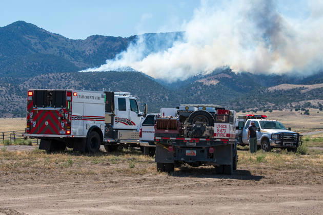 August 23, 2026, Elberta, Utah, USA: A plume of thick smoke rises into the sky above a mountain ridge as the Big Mountain Fire burns southwest of Elberta, Utah, United States, on August 23, 2026. A line of emergency response vehicles can be seen staged along a dirt road below the active wildland blaze. Elberta USA  - ZUMAm292 20260823_znp_m292_001 Copyright: xCharlesxMcClintockxWilsonx
