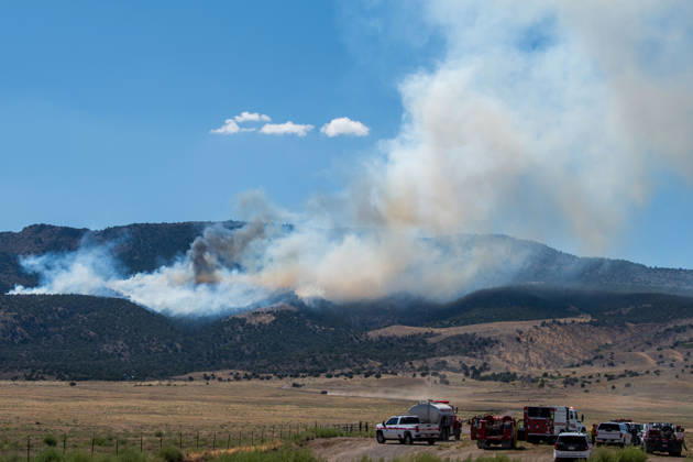 August 23, 2026, Elberta, Utah, USA: A plume of thick smoke rises into the sky above a mountain ridge as the Big Mountain Fire burns southwest of Elberta, Utah, United States, on August 23, 2026. A line of emergency response vehicles can be seen staged along a dirt road below the active wildland blaze. Elberta USA - ZUMAm292 20260823_znp_m292_008 Copyright: xCharlesxMcClintockxWilsonx