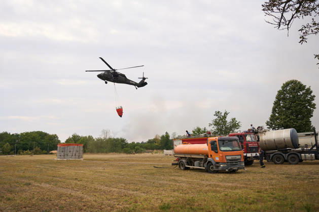 August 25, 2026, Susara, Vojvodina, Serbia: 2026825, Susara, Serbia - Two Sikorsky UH-60 Black Hawk helicopters are deployed to the village of Susara to help battle the severe wildfires devastating the Deliblato Sands (Deliblatska Pescara) Special Nature Reserve, refilling their buckets from a large portable water tank placed on a local football pitch. Susara Serbia - ZUMAd223 20260825_zip_d223_001 Copyright: xMarkoxDimicx