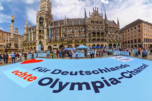 Für Deutschlaands echte Olympia-Chance! Münchner Olympia-Bewerbung mit Riesen-Banner auf dem Marienplatz, München, 26. August 2026 Deutschland, München, 26. August 2026, Für Deutschlaands echte Olympia-Chance! Münchner Olympia-Bewerbung mit 20 x 10 Mweter großem Banner, Marienplatz, mit Rathaus und Mariensäule, Countdown zur Entscheidung des Deutschen Olympischen Sportbunds, in genau einem Monat, Bayern