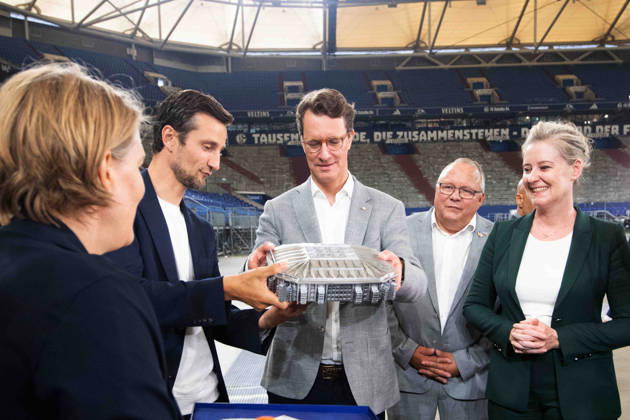 v.l. Bettina RUEHL-HAMERS, Rühl-Hamers, Vorstandsmitglied FC Schalke 04, CFO, Matthias TILLMANN, Vorstandsvorsitzender FC Schalke 04, ueberreicht ein Modell der Arena an Hendrik WUEST, Wüst, CDU, Ministerpraesident des Landes Nordrhein-Westfalen, Andrea HENZE, SPD, Oberbuergermeisterin der Stadt Gelsenkirchen, Hendrik WUEST, Wüst, CDU, Ministerpraesident des Landes Nordrhein-Westfalen, besucht das Stadion Veltins Arena des FC Schalke 04 (GE) am 28.08.2026 auf dem Trainingsgelaende in Gelsenkirchen Deutschland.