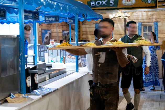 Eröffnung Plärrer in Augsburg. Ein Kellner in Lederhose trägt mehrere Teller mit Speisen durch das Festzelt auf dem Augsburger Herbstplärrer. Die Festgastronomie versorgt die zahlreichen Besucher des Volksfests mit Essen