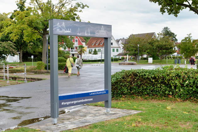 Langenargen Langenargen am Bodensee Langenargen, Baden-Württemberg, Deutschland, 28.08.2026. Ein Fotopunkt mit dem Schriftzug Langenargen und dem Hashtag langenargenambodensee steht in der Uferanlage von Langenargen. Auf dem Rahmen sind typische Motive des Ortes und des Bodensees stilisiert dargestellt. Passanten gehen nach einem Regenschauer durch die Anlage. Das Motiv zeigt Langenargen als touristisches Ausflugsziel am Bodensee. Copyright: xEibner-Pressefotox EP_EER