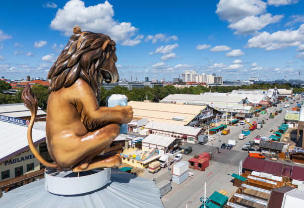 MUNICH, GERMANY - AUGUST 29, 2026: Oktoberfest Setup with Lion Statue and Beer Tents A large lion statue holding a beer stein overlooks the Theresienwiese during the setup phase of the 2026 Oktoberfest in Munich. Munich Germany