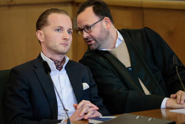 Windkraftbetrüger Hendrik Holt - Der Windkraftbetrüger Hendrik Holt (links) und sein und sein Verteidiger Maximilian Pancic warten am 07.03.2023 auf die Aussage von Ex-Gesundheitsminister Jens Spahn (CDU, nicht im Bild) im Masken-Deal-Prozess vor dem Landgericht Osnabrück (Niedersachsen, Deutschland). Holt wurde wegen banden- und gewerbsmäßigen Betrugs, Bestechung und Urkundenfälschung zu einer mehrjährigen Haftstrafe verurteilt; aktuell wird nach ihm gefahndet, nachdem er am 25. August 2026 nach einem genehmigten unbegleiteten Ausgang nicht in die Justizvollzugsanstalt zurückkehrte.
