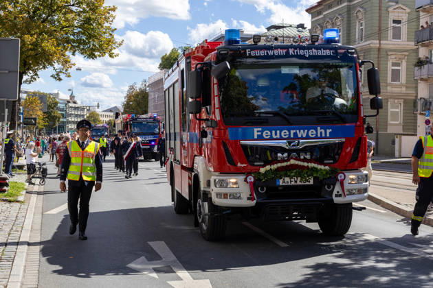 Traditioneller Plärrerumzug in Augsburg. Die Feuerwehr Kriegshaber nimmt mit einem geschmückten Einsatzfahrzeug und uniformierten Feuerwehrleuten am traditionellen Plärrerumzug durch Augsburg teil und zieht durch die Innenstadt