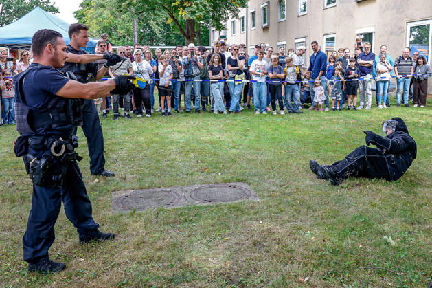 75 Jahre Bundespolizei - Bürgerfest der Bundespolizeidirektion Hannover Der Taser wird von Streifen der Bundespolizei Hannover seit Ende 2025 eingesetzt. Der Abschuss von bis zu zehn Elektrode auf eine bekleidete Person erfolgt aus 12 Meter Entfernung. Ein Strom mit maximal 883 Volt und 0,0020 Ampere pro Sekunde erfolgt für fünf Sekunden. Der Taser-Einsatz wird im Axon Gerät auslesbar elektronisch gespeichert. Der Beamte vorne links schießt zwei Elektroden auf die gepolsterte Person mit einer zerstörten Glasflasche ab. Der Beamte dahinter hat die Dienstpistole gezogen und dient als zusätzliche Absicherung. Hannover Bundespolizeidirektion Hannover, Niedersachsen, Region Hannover Germany