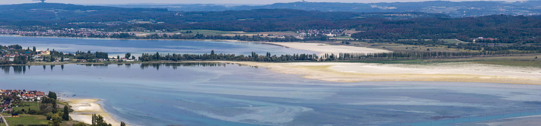 Ausblick auf die Insel Reichenau im Bodensee. Rechts der Reichenauer Damm mit Platanenallee, ein Teil der Deutschen Allenstraße. Das Seeufer zeigt den niedrigen Wasserstand nach einem heißen Sommer. 27.08.2026, Ermatingen, Kanton Thurgau, Schweiz
