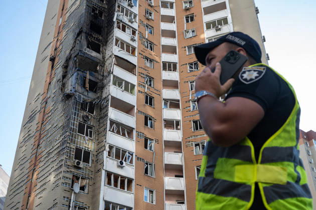 A National Police officer in a high-visibility vest talks on the phone outside a 24-storey apartment block damaged by a Russian attack in the Darnytskyi district of Kyiv, Ukraine, September 9, 2026. On Wednesday morning, September 9, a Russian drone hit the 24-storey building on the 12th floor. According to police, five people were injured, including a pregnant woman. (Photo by Danylo Antoniuk Ukrinform) Apartment block hit by Russian drone in Kyiv  Copyright: xDanyloxAntoniukx