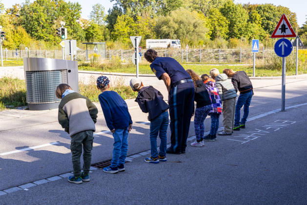 Schulwegtraining mit der Verkehrspolizeiinspektion Augsburg vor dem Schulanfang in Bayern. Kinder üben beim Schulwegtraining in Augsburg mit einer Polizistin das sichere Überqueren einer Straße. Vor dem Queren schauen sie aufmerksam nach links und rechts und trainieren richtiges Verkehrsverhalten