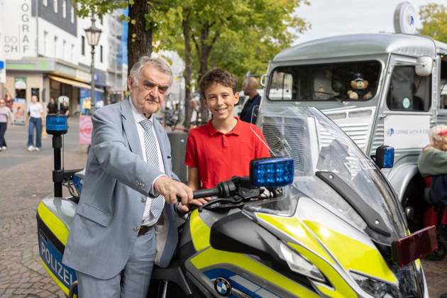 Coffee with a Cop in Siegburg - 11.09.26 Geburtstagsbild mit Maximilian (jetzt 12 Jahre alt) mit dem Innenminister am Motorrad - Im Rahmen der bundesweiten Polizeiaktion Coffee with a Cop besucht NRW-Innenminister Herbert REUL (CDU) den Infostand der Kreispolizeibehörde Rhein-Sieg-Kreis auf dem Unteren Marktplatz in Siegburg. Bei Kaffee, Kakao oder Tee kommen Polizeibeamtinnen und Polizeibeamte mit Bürgerinnen und Bürgern ins ungezwungene Gespräch. Siegburg Nordrhein-Westfalen Deutschland Copyright: xMarcxJohnx
