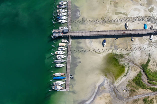 Wetterfeature, Bei sonnigem Spätsommerwetter am Bodensee liegen einige Boote aufgrund des niedrigen Wasserstands auf dem Trockenen. Gleichzeitig zeigt sich der Bodensee von seiner malerischen Seite das Wasser schimmert bei strahlendem Sonnenschein grünlich-blau, während sich die Uferlandschaft unter nahezu wolkenlosem Himmel präsentiert. (Aufnahme mit einer Drohne) Moos Baden-Württemberg Deutschland Moos