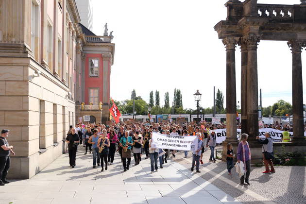 Demonstranten laufen mit Banner Netzwerk Omas gegen Rechts Brandenburg um den Landtag während einer Demonstration für die Überprüfung rechtsextremer Parteien durch das Bundesverfassungsgericht, Alter Markt, Potsdam, 12. September 2026. Prüf-Demo in Potsdam