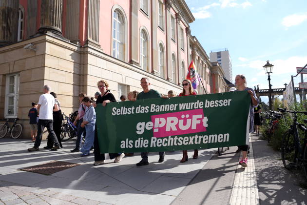 Demonstranten laufen mit Banner Selbst das Banner wurde besser geprüft als die Rechtsextremen um den Landtag während einer Demonstration für die Überprüfung rechtsextremer Parteien durch das Bundesverfassungsgericht, Alter Markt, Potsdam, 12. September 2026. Prüf-Demo in Potsdam