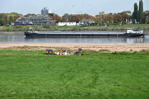 Das Niedrigwasser im Rhein hat eine grosse Sandbank freigelegt, Steine und Sand am Ufer, nahe der Theodor Heuss Bruecke, ein Frachtschiff faehrt in der Fahrrinne, im Vordergrund Treibgut, Autoreifen und Unrat wurden vom Niedrigwasser freigegeben, Unbekannte haben den Muell gesammelt und am Ufer zur Abholung abgelegt, Niedrigwasser im Rhein bei Duesseldorf, Duesseldorf am 28.09.2026,