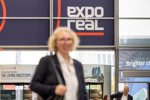 EXPO REAL 2026 in München 05.10.2026: Weiblicher Fachbesucher auf dem Weg in die Messehallen auf dem Gelände Messe München. Erster Messetag der EXPO REAL 2026. Die internationale Fachmesse für Immobilien, Investitionen und Infrastruktur findet vom 5. bis 7. Oktober 2026 in München statt und bringt Vertreter der Immobilienwirtschaft, Investoren, Projektentwickler, Finanzierer sowie weitere Akteure der Branche zusammen. Muenchen Messe Bayern Deutschland
