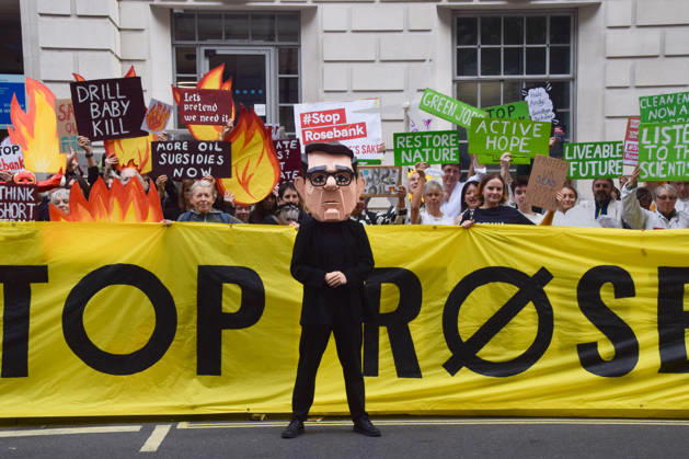 October 6, 2026, London, England, United Kingdom: Activists from the climate action group Fossil Free London stage a protest against the Rosebank oil field and the Jackdaw gas field outside the Department for Energy Security and Net Zero. Activists dressed as angels urge a protester wearing an Andy Burnham mask to stop the fossil fuel projects in the North Sea while activists dressed as demons urge him to drill for more oil. London United Kingdom  - ZUMAv130 20261006_zip_v130_033 Copyright: xVukxValcicx