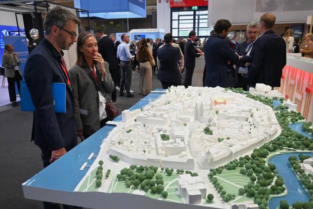 Die EXPO REAL 2026 findet aktuell auf dem Messegelände der Messe München statt. Sie ist Europas grösste internationale Fachmesse für Immobilien, Investitionen und Infrastruktur. Foto: Besucher betrachten an einem Messestand ein Modell.