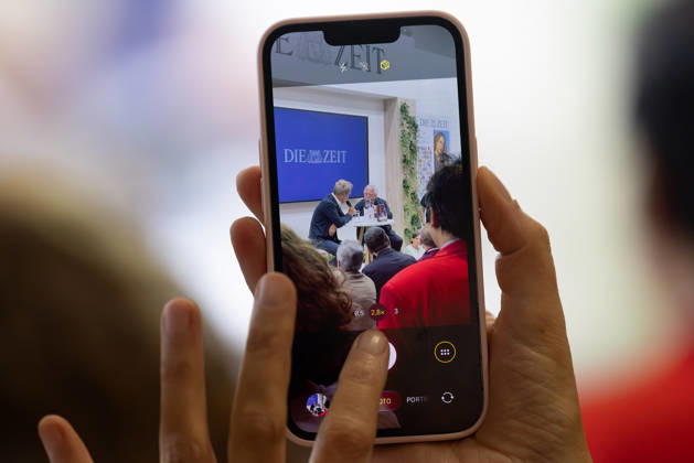 Buchmesse Frankfurt 2026 Eine Buchmesse-Besucherin filmt Wolf Biermann, der mit ZEIT-Redakteur Volker Weidermann über die Auszüge aus seinen Tagebüchern und sein bewegtes Leben spricht., Frankfurt am Main Hessen Deutschland Messegelände