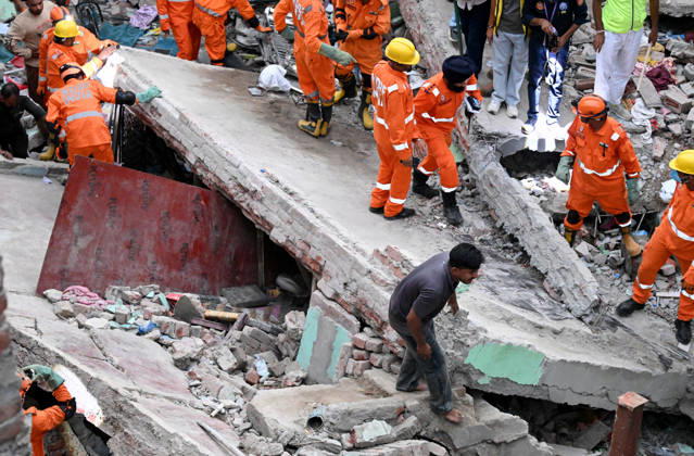 NEW DELHI, INDIA - OCTOBER 7: National Disaster Response Force (NDRF) jawans, Delhi Fire Service personnel, and local residents navigate heavy rubble during a search and rescue operation after a four-storey residential building collapsed in the New Seemapuri area of Shahdara on October 7, 2026, in New Delhi, India. The structural collapse occurred around 3:30 PM behind the local fish market, trapping multiple residents under concrete slabs and damaging two adjoining houses. At least one minor died while eight people were rescued and rushed to Rajiv Gandhi Super Speciality Hospital for emergency medical treatment as sniffer dogs and excavators worked late into the evening to locate remaining trapped survivors. (Photo by Ishant Chauhan Hindus