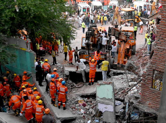 NEW DELHI, INDIA - OCTOBER 7: National Disaster Response Force (NDRF) jawans, Delhi Fire Service personnel, and local residents navigate heavy rubble during a search and rescue operation after a four-storey residential building collapsed in the New Seemapuri area of Shahdara on October 7, 2026, in New Delhi, India. The structural collapse occurred around 3:30 PM behind the local fish market, trapping multiple residents under concrete slabs and damaging two adjoining houses. At least one minor died while eight people were rescued and rushed to Rajiv Gandhi Super Speciality Hospital for emergency medical treatment as sniffer dogs and excavators worked late into the evening to locate remaining trapped survivors. (Photo by Ishant Chauhan Hindus
