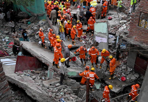 NEW DELHI, INDIA - OCTOBER 7: National Disaster Response Force (NDRF) jawans, Delhi Fire Service personnel, and local residents navigate heavy rubble during a search and rescue operation after a four-storey residential building collapsed in the New Seemapuri area of Shahdara on October 7, 2026, in New Delhi, India. The structural collapse occurred around 3:30 PM behind the local fish market, trapping multiple residents under concrete slabs and damaging two adjoining houses. At least one minor died while eight people were rescued and rushed to Rajiv Gandhi Super Speciality Hospital for emergency medical treatment as sniffer dogs and excavators worked late into the evening to locate remaining trapped survivors. (Photo by Ishant Chauhan Hindus