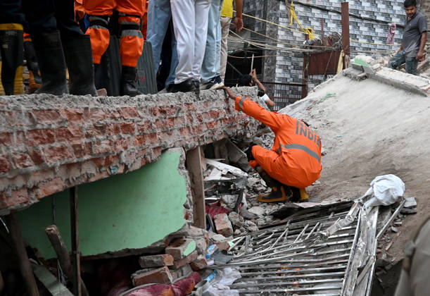 NEW DELHI, INDIA - OCTOBER 7: National Disaster Response Force (NDRF) jawans, Delhi Fire Service personnel, and local residents navigate heavy rubble during a search and rescue operation after a four-storey residential building collapsed in the New Seemapuri area of Shahdara on October 7, 2026, in New Delhi, India. The structural collapse occurred around 3:30 PM behind the local fish market, trapping multiple residents under concrete slabs and damaging two adjoining houses. At least one minor died while eight people were rescued and rushed to Rajiv Gandhi Super Speciality Hospital for emergency medical treatment as sniffer dogs and excavators worked late into the evening to locate remaining trapped survivors. (Photo by Ishant Chauhan Hindus