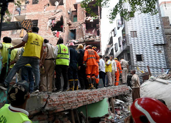 NEW DELHI, INDIA - OCTOBER 7: National Disaster Response Force (NDRF) jawans, Delhi Fire Service personnel, and local residents navigate heavy rubble during a search and rescue operation after a four-storey residential building collapsed in the New Seemapuri area of Shahdara on October 7, 2026, in New Delhi, India. The structural collapse occurred around 3:30 PM behind the local fish market, trapping multiple residents under concrete slabs and damaging two adjoining houses. At least one minor died while eight people were rescued and rushed to Rajiv Gandhi Super Speciality Hospital for emergency medical treatment as sniffer dogs and excavators worked late into the evening to locate remaining trapped survivors. (Photo by Ishant Chauhan Hindus