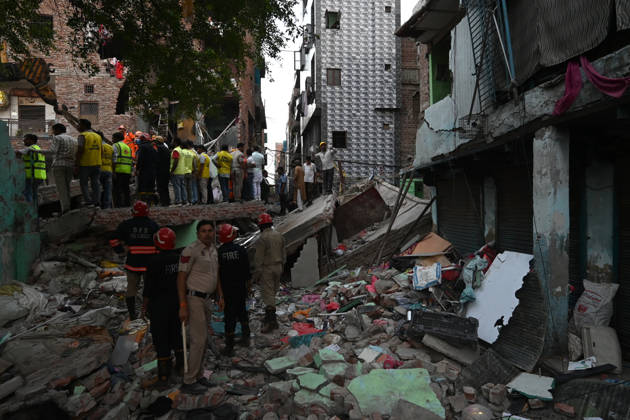 NEW DELHI, INDIA - OCTOBER 7: National Disaster Response Force (NDRF) jawans, Delhi Fire Service personnel, and local residents navigate heavy rubble during a search and rescue operation after a four-storey residential building collapsed in the New Seemapuri area of Shahdara on October 7, 2026, in New Delhi, India. The structural collapse occurred around 3:30 PM behind the local fish market, trapping multiple residents under concrete slabs and damaging two adjoining houses. At least one minor died while eight people were rescued and rushed to Rajiv Gandhi Super Speciality Hospital for emergency medical treatment as sniffer dogs and excavators worked late into the evening to locate remaining trapped survivors. (Photo by Ishant Chauhan Hindus