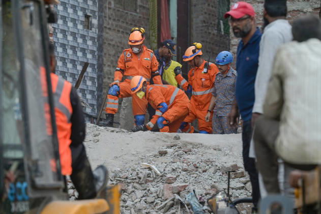 NEW DELHI, INDIA - OCTOBER 7: National Disaster Response Force (NDRF) jawans, Delhi Fire Service personnel, and local residents navigate heavy rubble during a search and rescue operation after a four-storey residential building collapsed in the New Seemapuri area of Shahdara on October 7, 2026, in New Delhi, India. The structural collapse occurred around 3:30 PM behind the local fish market, trapping multiple residents under concrete slabs and damaging two adjoining houses. At least one minor died while eight people were rescued and rushed to Rajiv Gandhi Super Speciality Hospital for emergency medical treatment as sniffer dogs and excavators worked late into the evening to locate remaining trapped survivors. (Photo by Raj K Raj Hindustan T