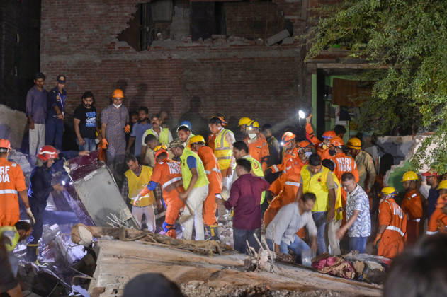 NEW DELHI, INDIA - OCTOBER 7: National Disaster Response Force (NDRF) jawans, Delhi Fire Service personnel, and local residents navigate heavy rubble during a search and rescue operation after a four-storey residential building collapsed in the New Seemapuri area of Shahdara on October 7, 2026, in New Delhi, India. The structural collapse occurred around 3:30 PM behind the local fish market, trapping multiple residents under concrete slabs and damaging two adjoining houses. At least one minor died while eight people were rescued and rushed to Rajiv Gandhi Super Speciality Hospital for emergency medical treatment as sniffer dogs and excavators worked late into the evening to locate remaining trapped survivors. (Photo by Raj K Raj Hindustan T